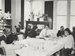 black and white photo of group of people meeting around table, circa 1970s