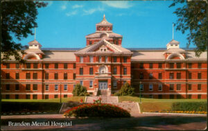 brightly coloured image of large, imposing old multi-story brick building with beautiful garden