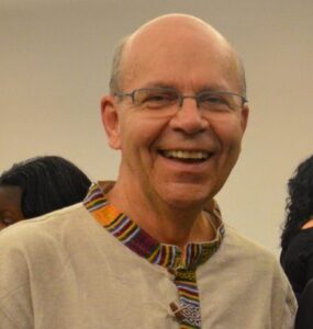 Smiling middle-aged man with glasses, bookshelves behind