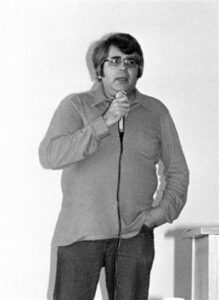 Young middle-aged man with glasses speaking into mic