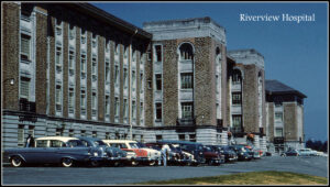 imposing entrance to stone or brick institutional building, 1950s cars parked out front