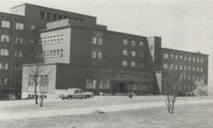 old black and white photo of large hospital building with car in front