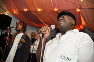colour photo of two men at microphones and other musicians behind