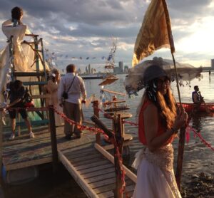 colour photo of man and other people on pier, carnival/party scene 