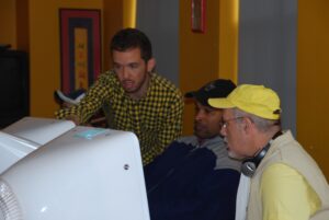 colour photo of 3 men looking at computer screen