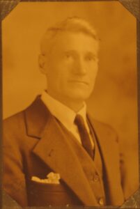 white haired man in an old fashioned suit and tie