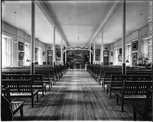 Rectangular room in which there are several rows of benches in front of a stage