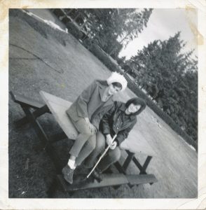 2 young women sitting on picnic table in playing field