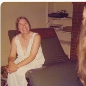 smiling woman wearing nightie sitting on couch