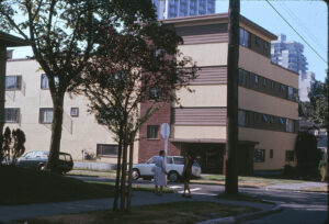 older low rise apartment building with cars parked in front