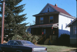 old house and front garden with cars parked in front