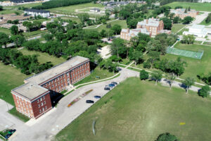 aerial colour photograph of old red brick institutional buildings surrounded by trees and green fields