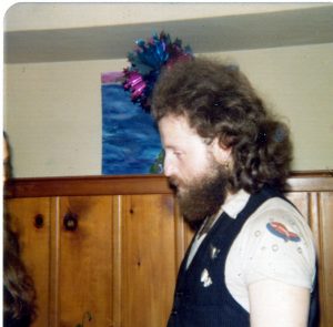 head and shoulders shot of man with thick curly dark hair and facial hair